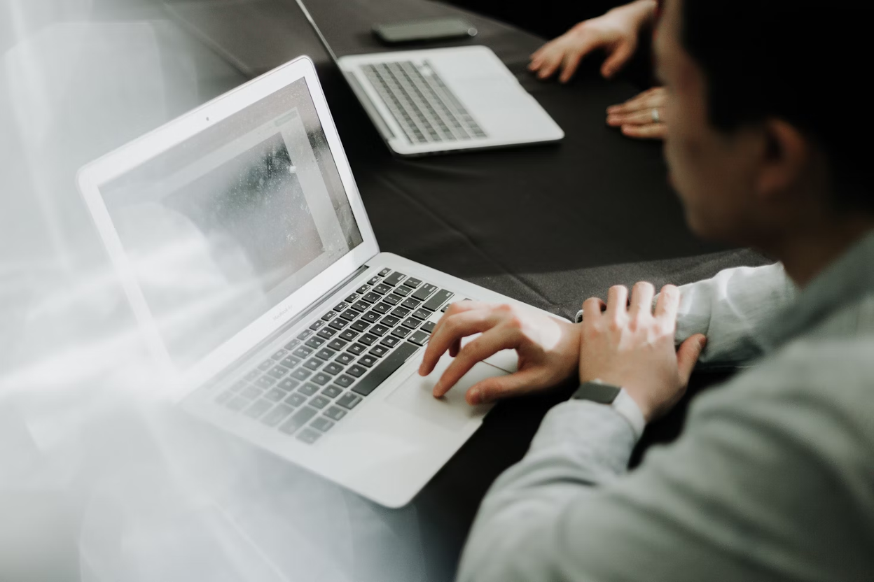A man in business attire sitting in front of a laptop