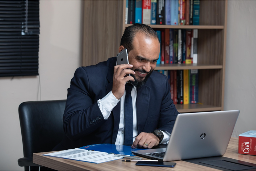 Business professional on phone call while reviewing financial documents and using a computer for debt collection