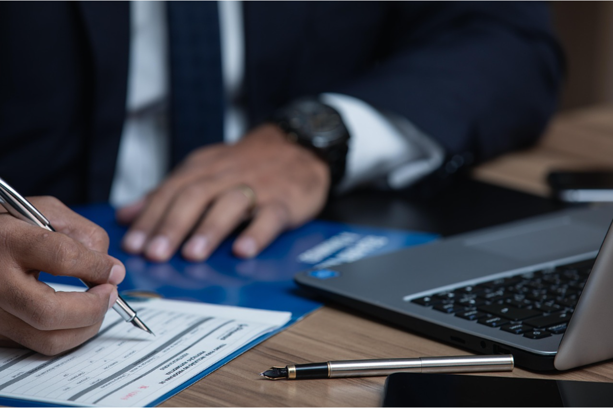 Business professional reviewing legal documents and financial paperwork at desk.