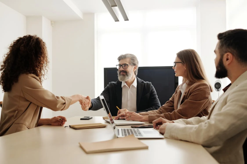 Business professionals shaking hands across a conference table during a meeting in a modern office