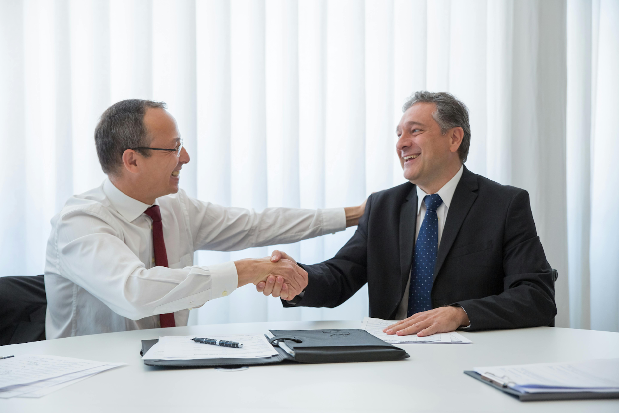 Two business professionals shaking hands across the desk