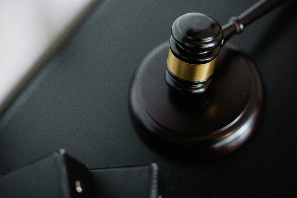 Wooden gavel with gold band resting on a dark surface