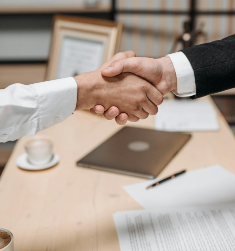 A handshake exchange across a desk after a payment agreement was reached, with documents visible