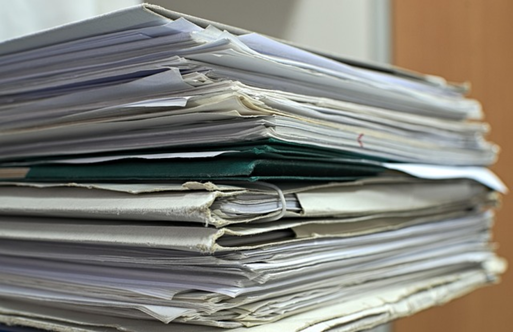 A tall stack of organized paper documents and folders