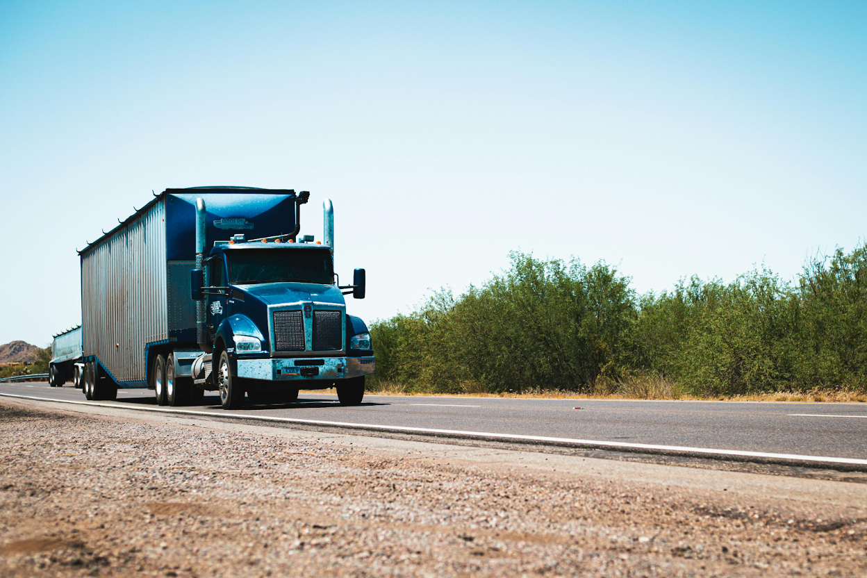 Blue semi-truck with trailer driving on desert highway