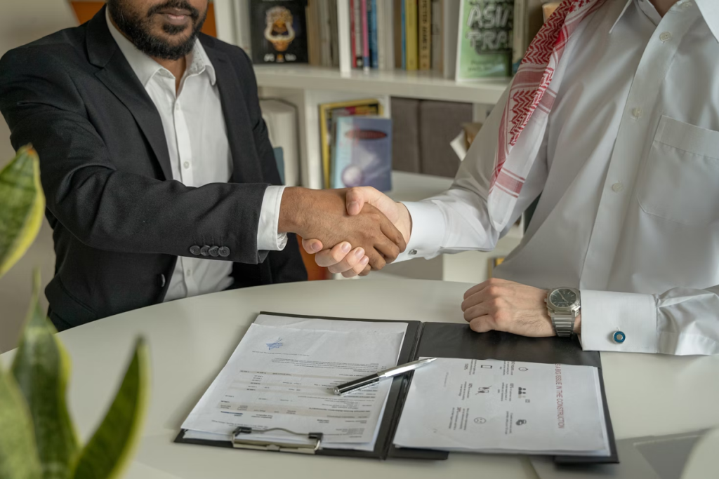 Business professionals shaking hands over ownership transfer contract agreement in a modern office setting