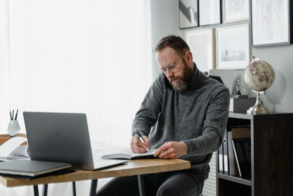 Finance specialist organizing invoice documents and payment records at an office desk with a computer