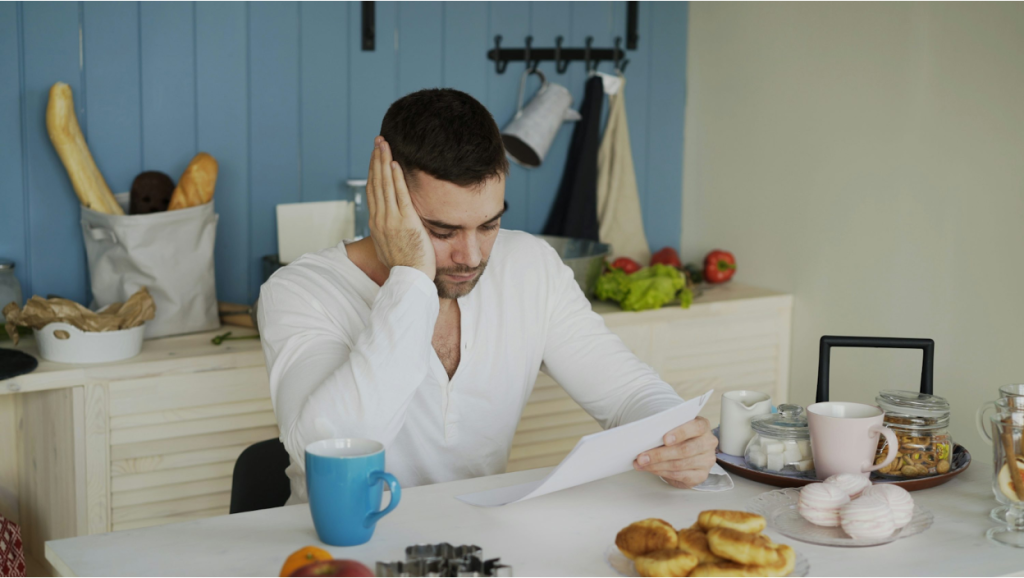Man in a white shirt looking stressed while reading a document