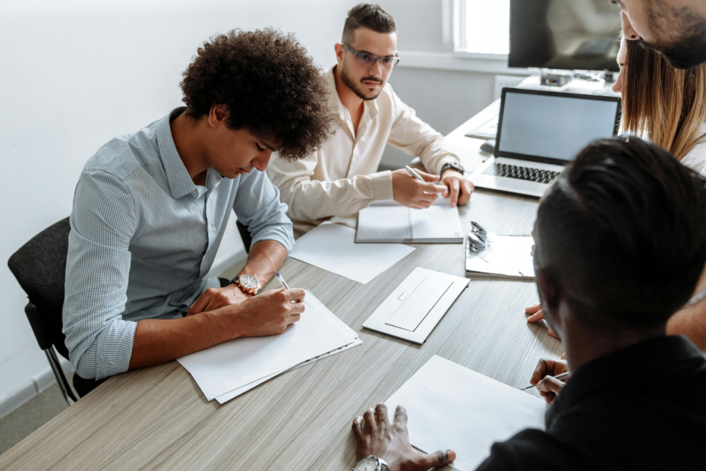 People signing documents at a desk in an office setting