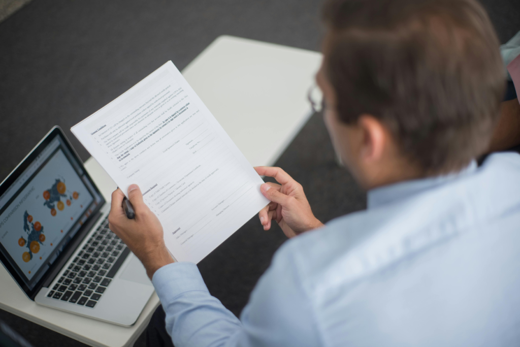 Person reviewing documents with a laptop