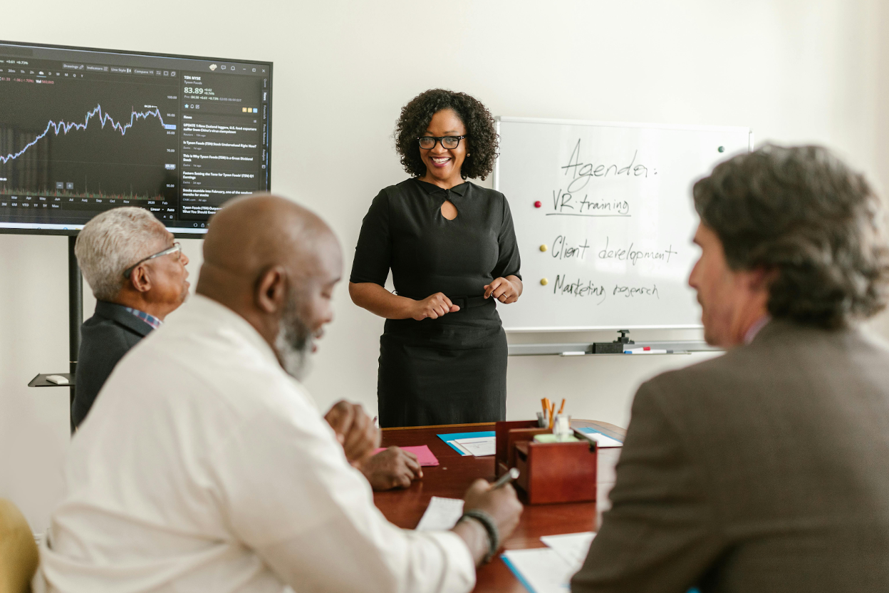 Professional presenting to a team in a conference room with a financial chart on screen