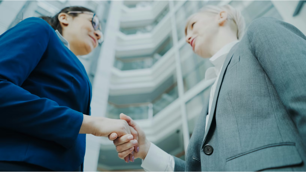 Two business professionals shaking hands in an office setting