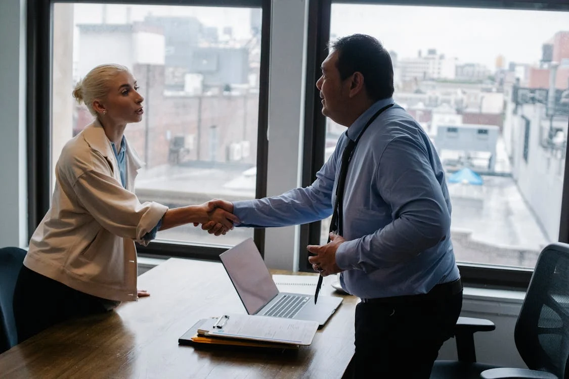 Business professionals shaking hands during a meeting in an office.