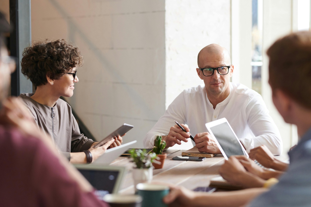 Business team meeting around a table in a bright, modern office.
