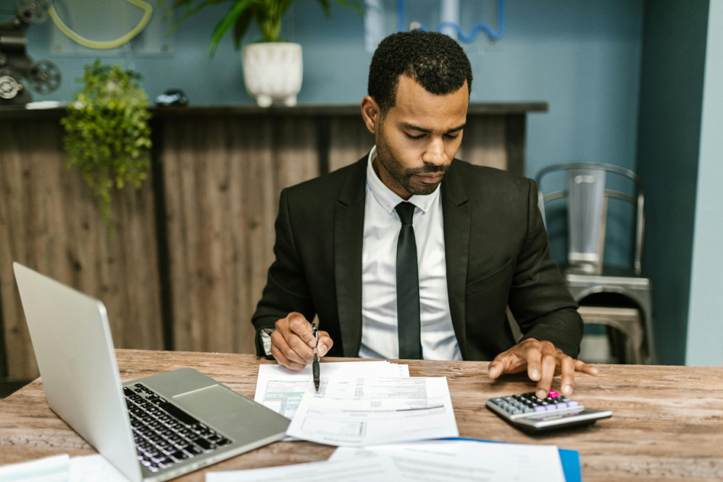 Businessman in a suit working at a desk with a laptop, calculator, and financial documents
