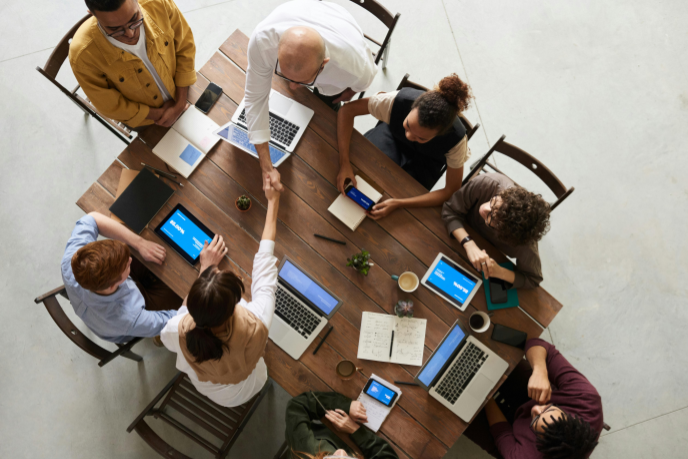 Overhead view of a business meeting with people around a conference table, two shaking hands.