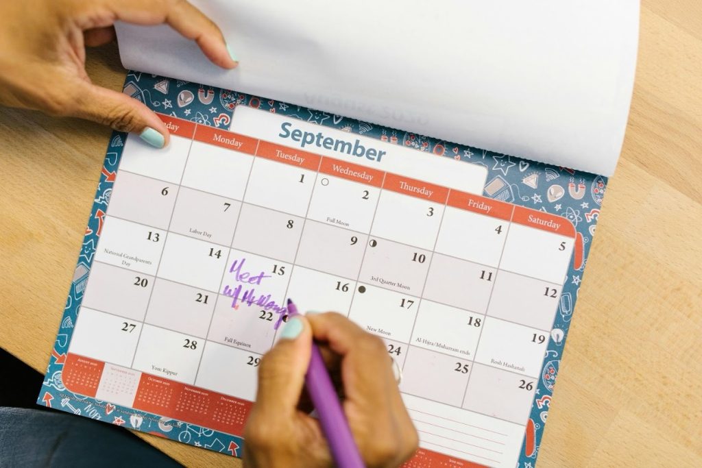 Person checking and marking payment dates on a calendar
