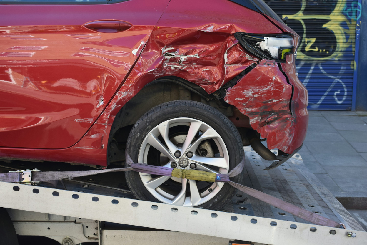 Red damaged car being loaded onto a tow truck