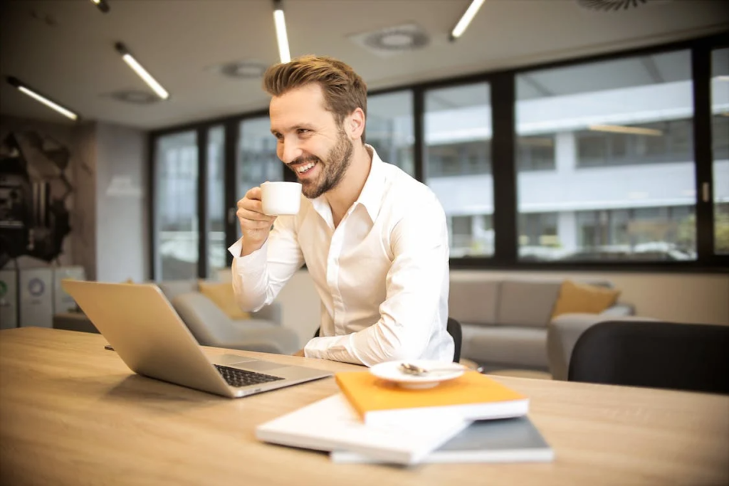 Smiling businessman wearing glasses working on a laptop at a desk in a modern office
