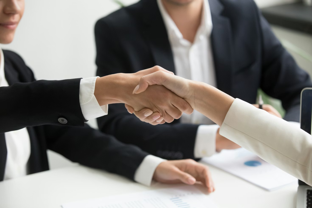 Two business professionals shaking hands across a desk