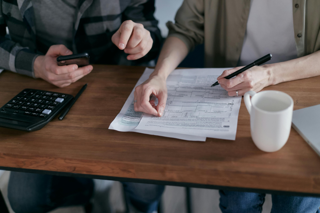 Two people reviewing financial documents at a wooden table.