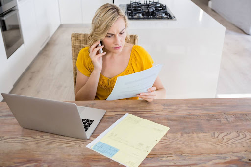 Business owner at a desk reviewing past-due invoices and payment records.