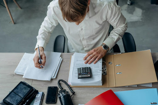 Business professional in an office reviewing financial documents and invoices on a desk.