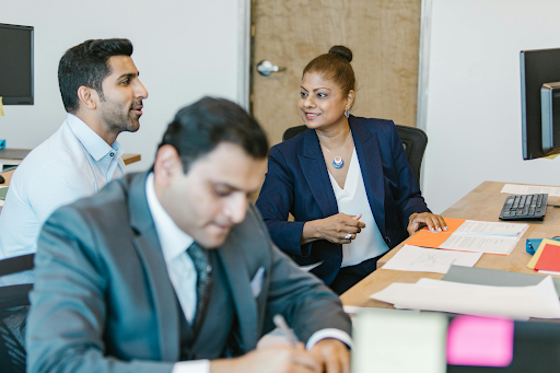 Businesswoman in a blazer discussing with colleagues in an office meeting with documents
