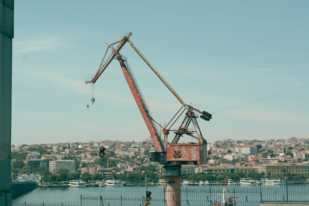 Large industrial port crane at a waterfront with a coastal city skyline in the background