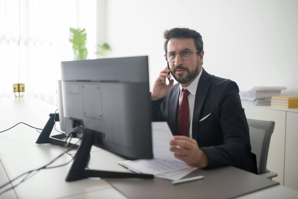 Property manager working at desk with computer, phone, and documents.