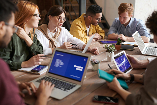 Team collaborating with laptops and tablets in a modern workspace environment.