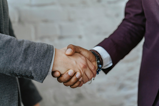 Two business professionals shaking hands, wearing suit jackets.