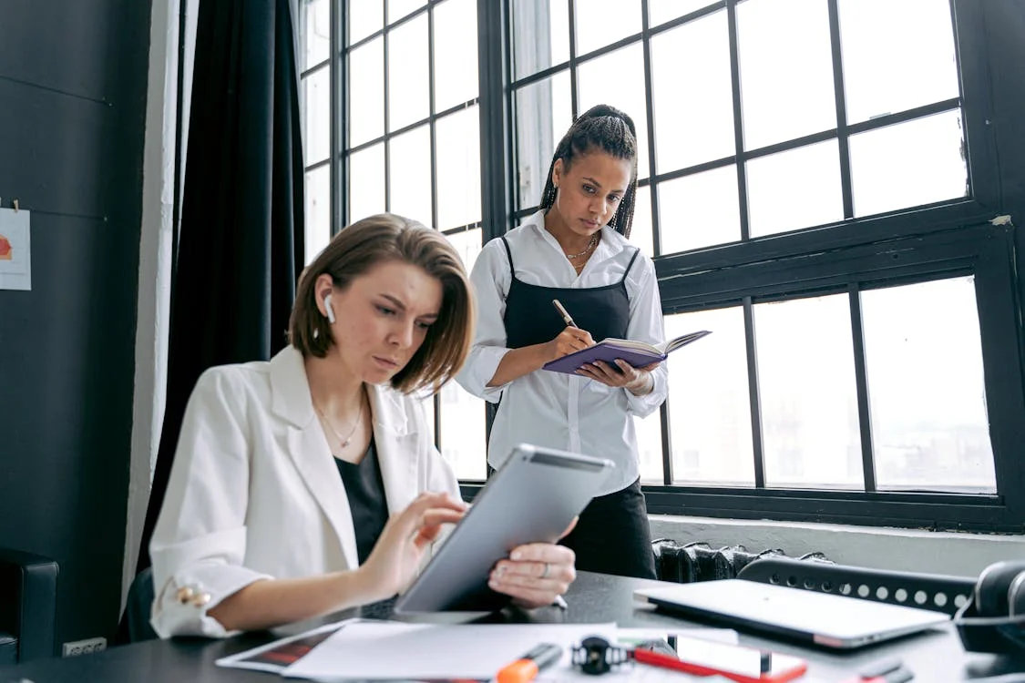 Two businesswomen collaborating on a project in a modern workspace.