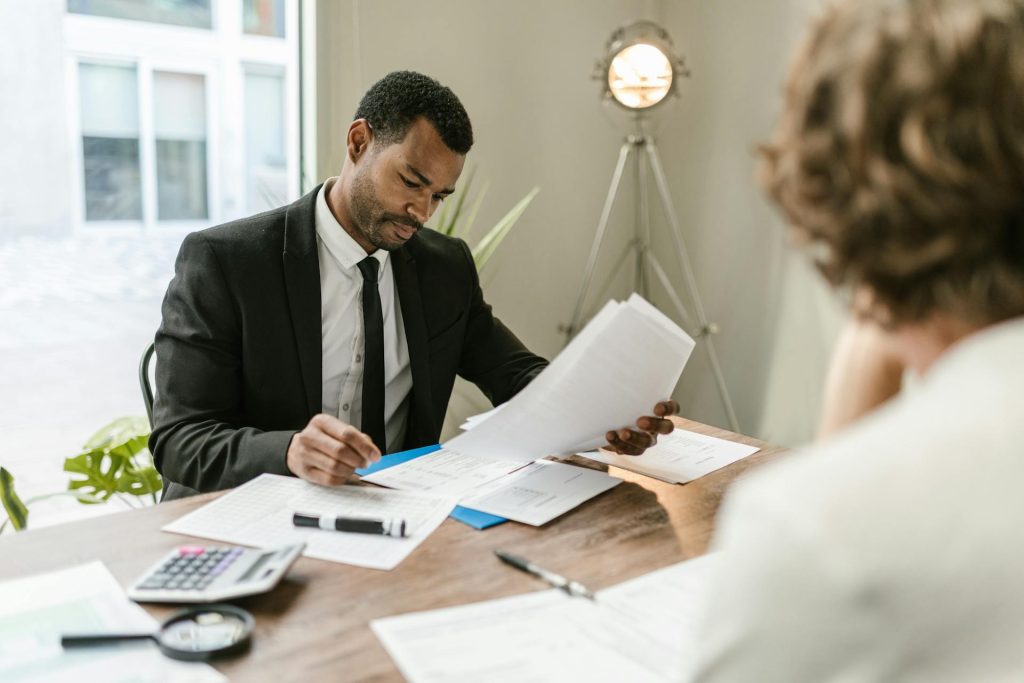 Business professional in a suit reviewing documents at a desk with a calculator and paperwork nearby