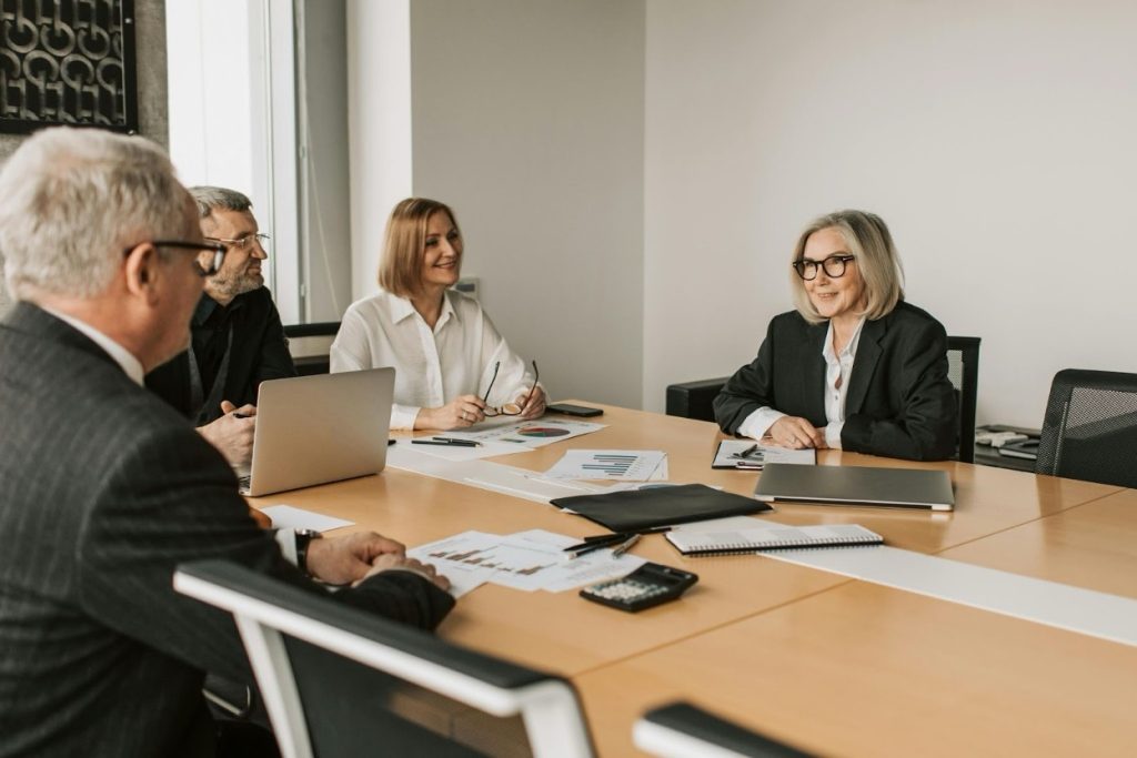 Business professionals in a conference room discussing financial strategy with documents and laptops