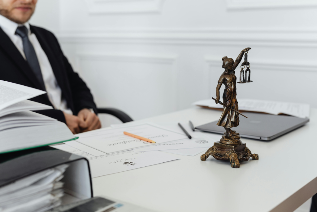 Lady Justice statue on desk with legal documents, laptop, and a business professional in a suit reviewing paperwork