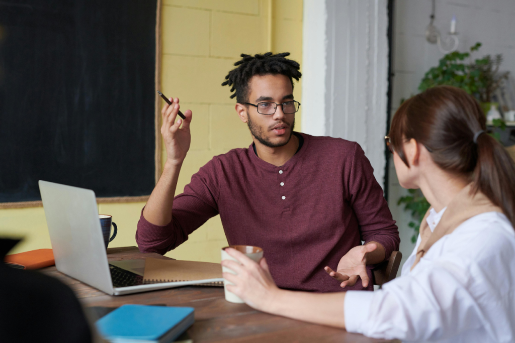 Two professionals discussing business at a desk in a modern office setting