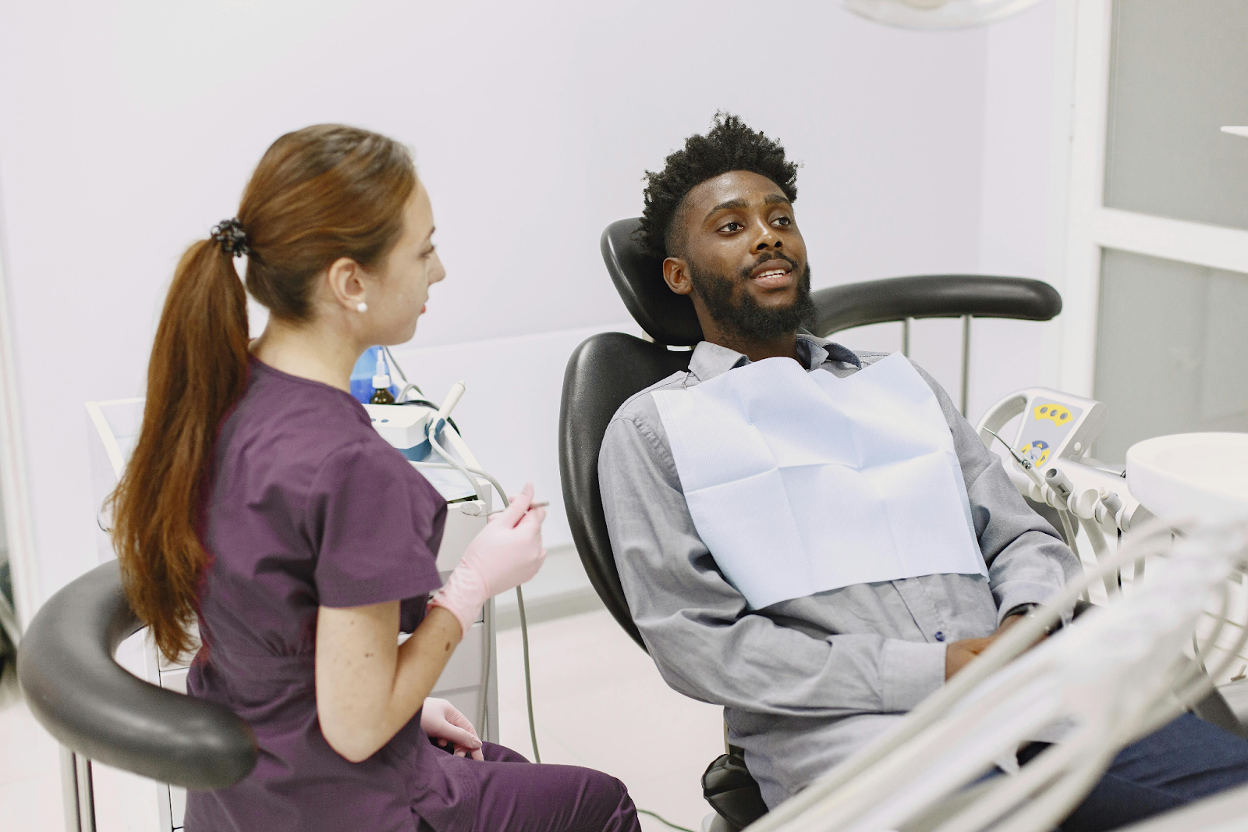 A dental professional in scrubs consulting with a patient seated in a dental chair