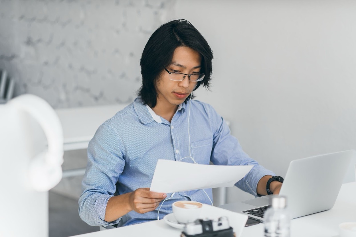 Business professional reviewing an overdue invoice at a desk with a laptop and financial documents