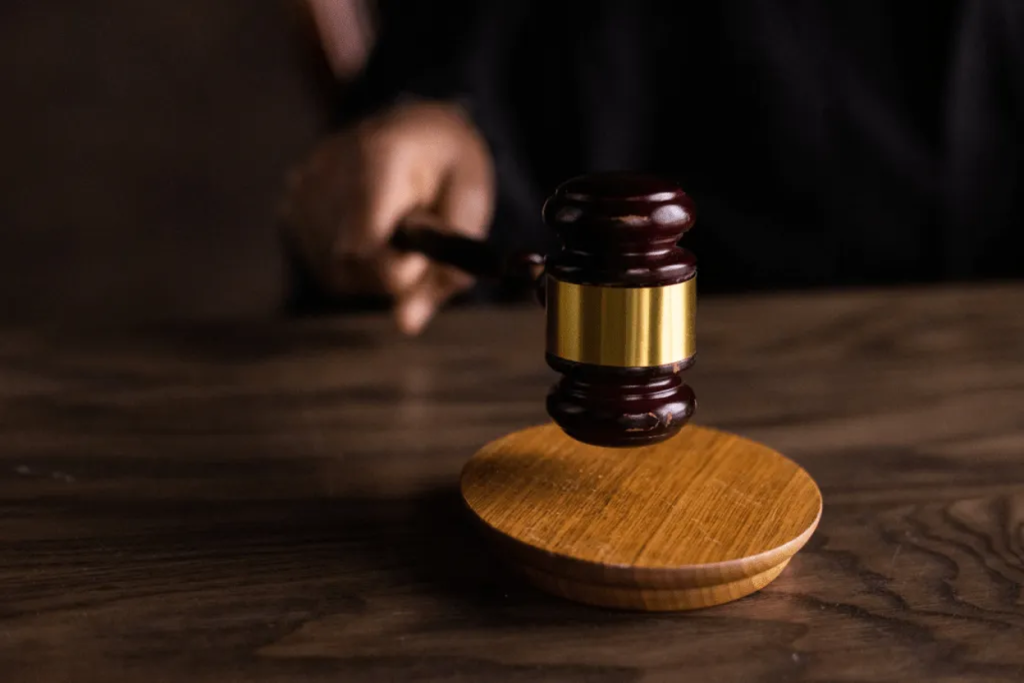 Close-up of a wooden judge's gavel resting on a sound block on a dark wooden desk