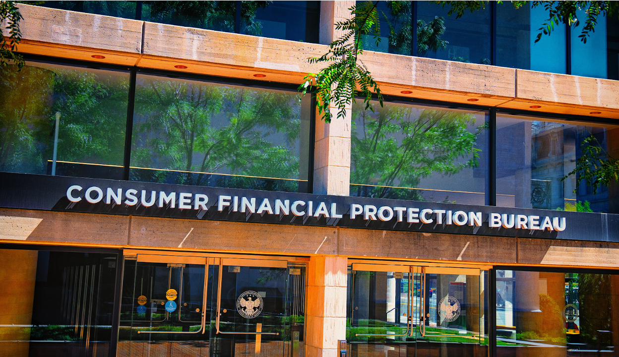 Exterior entrance of the Consumer Financial Protection Bureau building with signage and glass doors. (Image courtesy of Wikimedia Commons)