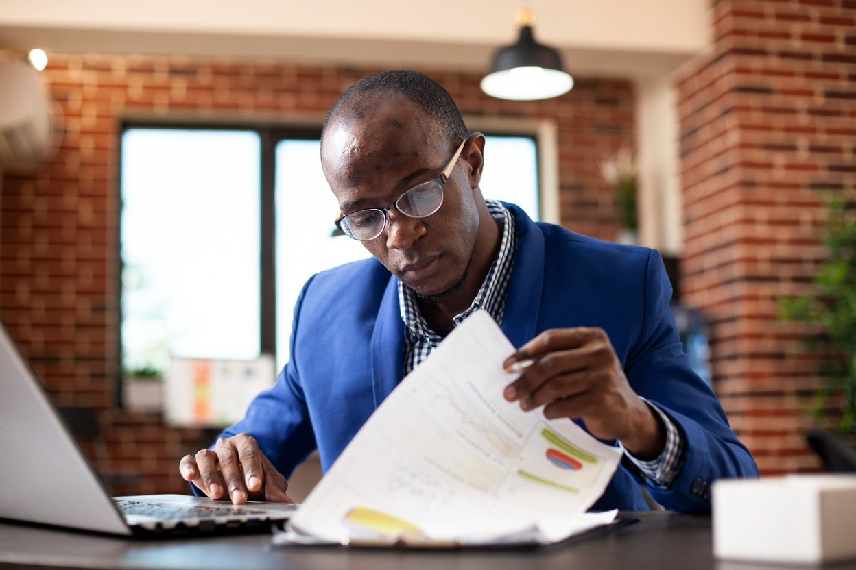 Financial professional reviewing unpaid invoices and collection reports at an office desk