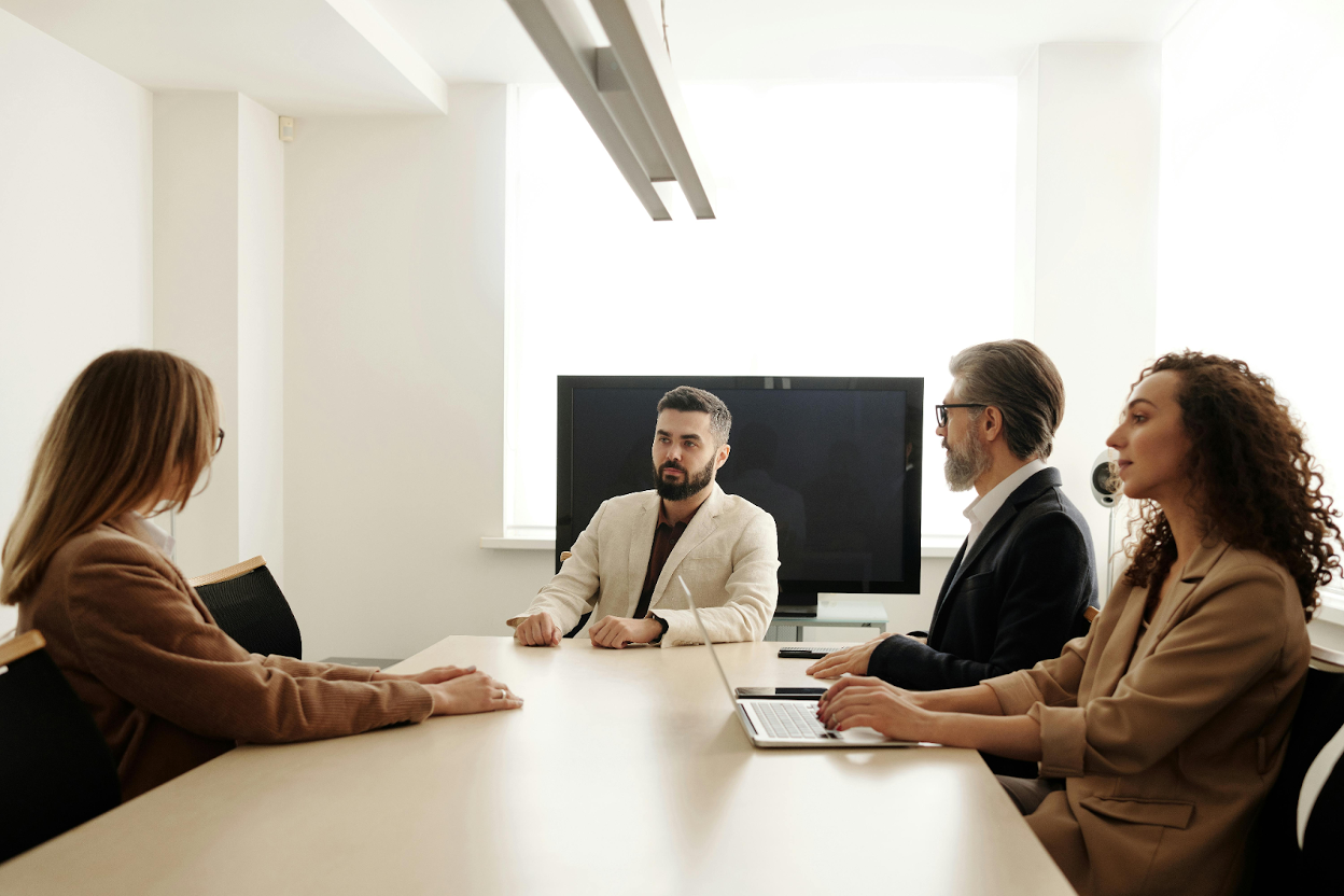 Four business professionals in formal attire meeting around a conference table in a modern office