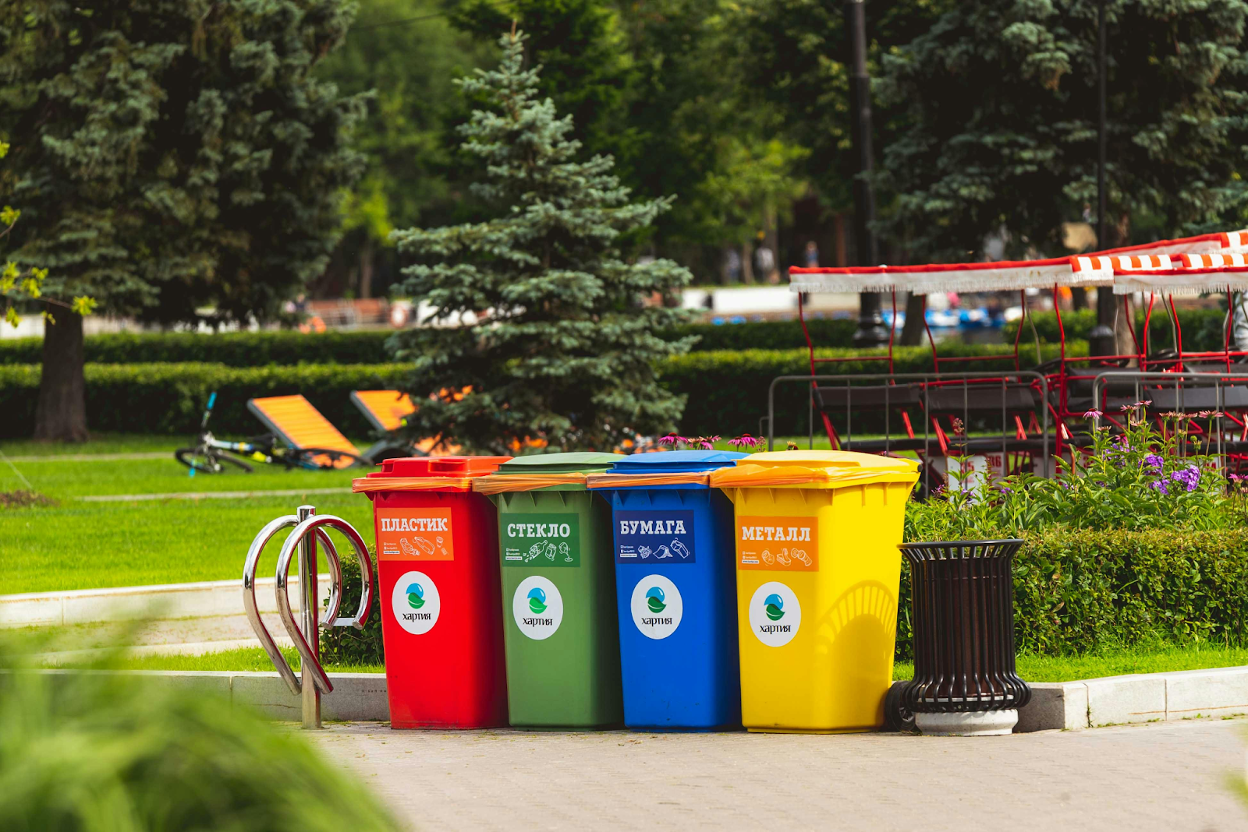 Four colorful recycling bins lined up in a park